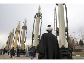 FILE - In this Feb. 3, 2019 file photo, an Iranian clergyman looks at domestically built surface to surface missiles displayed by the Revolutionary Guard in a military show marking the 40th anniversary of the Islamic Revolution, at Imam Khomeini Grand Mosque in Tehran, Iran. On Monday, April 8, 2019, the Trump administration designated Iran's Revolutionary Guard a "foreign terrorist organization" in an unprecedented move against a national armed force. Iran's Revolutionary Guard Corps went from being a domestic security force with origins in the 1979 Islamic Revolution to a transnational fighting force.