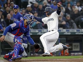 Seattle Mariners' Ryon Healy, right, slides in safely to home to score as Texas Rangers catcher Isiah Kiner-Falefa waits for the ball in the first inning of a baseball game Thursday, April 25, 2019, in Seattle.
