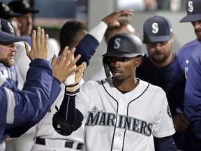 Seattle Mariners' Dee Gordon is congratulated in the dugout after scoring against the Los Angeles Angels in the sixth inning of a baseball game Tuesday, April 2, 2019, in Seattle.