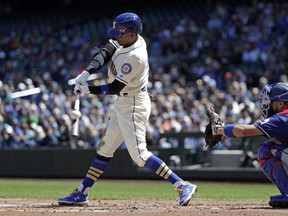 Seattle Mariners' Dee Gordon, left, swings and just misses to strike out as Texas Rangers catcher Isiah Kiner-Falefa waits for the ball in the first inning of a baseball game Sunday, April 28, 2019, in Seattle.