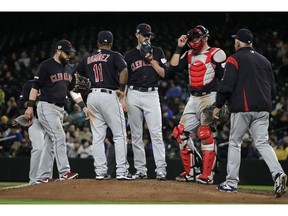 Cleveland Indians starting pitcher Shane Bieber, center, talks with teammates as pitching coach Carl Willis, right, arrives for a mound conference during the sixth inning of the team's baseball game against the Seattle Mariners, Tuesday, April 16, 2019, in Seattle.