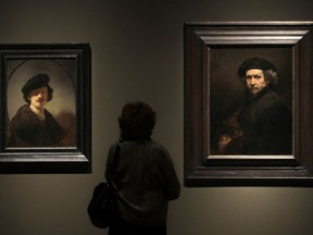 FILE - In this file photo dated Thursday, Feb. 16, 2012, a visitor views two self portraits by 17th century Dutch master Rembrandt at the Cleveland Museum of Art's 'Rembrandt in America' exhibition in Cleveland, USA.  It is announced Monday April 8, 2019, Dutch soccer teams will be playing with the official soccer ball inscribed with Rembrandt's face and extracts from his work in the Dutch soccer league next season, marking the 350th anniversary of his death.