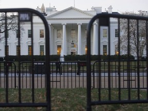 In this March 24, 2019 photo, The White House is seen behind security barriers in Washington. A White House official turned whistleblower says dozens of people in President Donald Trump's administration were granted access to classified information despite "disqualifying issues" in their backgrounds including concerns about foreign influence, drug use and criminal conduct.
