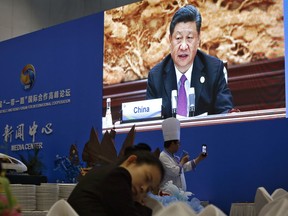 A chef takes a selfie near a live broadcast image of Chinese President Xi Jinping speaking at the leaders summit of the Belt and Road Forum, at the media center in Beijing, Saturday, April 27, 2019.