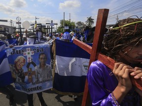 Anti-government protesters join a Stations of the Cross procession on Good Friday, carrying signs demanding the release of political prisoners in Managua, Nicaragua, Friday, April 19, 2019. Good Friday religious processions in Nicaragua's capital have taken a decidedly political tone as people have seized on a rare opportunity to renew protests against the government of President Daniel Ortega.