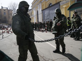 Soldiers guard an entrance while students evacuate from the Alexander Mozhaysky Military Space Academy in St. Petersburg, Russia, Tuesday, April 2, 2019. Russian news agencies are reporting a blast has occurred inside the prestigious Mozhaisky Academy in St. Petersburg which trains officers for missile defense troops.
