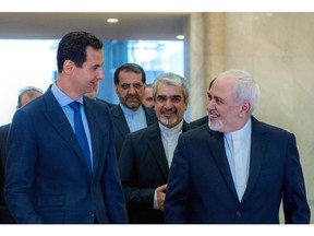 This photo released on the official Facebook page of Syrian Presidency shows Syrian President Bashar Assad, left, speaking with Iranian Foreign Minister Mohammad Javad Zarif, right, in Damascus, Syria, Tuesday, April 16, 2019. Zarif has blasted upon arrival in Syria the Trump administration decision to designate Tehran's Revolutionary Guards Corps a terrorist organization calling it a "stupid act." (Syrian Presidency Facebook page via AP)