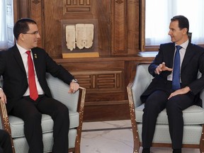 In this photo released by the Syrian official news agency SANA, Syrian President Bashar Assad, right, meets with Venezuelan Foreign Minister Jorge Arreaza, in Damascus, Syria, Thursday, April 4, 2019. Syria's Foreign Minister Walid al-Moallem said U.S. President Donald Trump's administration "lies" all the time about withdrawing its troops from the country.  Al-Moallem also said Trump's decision to recognize Israeli sovereignty over the occupied Golan Heights only serves to increase America's isolation in the world "even among its closest allies." (SANA via AP)