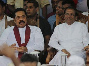 FILE - In this Nov. 5, 2018, file photo, Sri Lankan President Maithripala Sirisena, right, and his newly appointed prime minister Mahinda Rajapaksa, center attend a rally held outside the parliamentary complex as a police officer tries to control the crowd in Colombo, Sri Lanka. Government dysfunction and an intelligence failure that preceded the Easter Sunday bombings that killed 253 people in Sri Lanka are traced to simmering divisions between the president and prime minister after a weekslong political crisis that crippled the country last year.