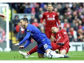 Chelsea's Eden Hazard, left, duels for the ball with Liverpool's Fabinho during the English Premier League soccer match between Liverpool and Chelsea at Anfield stadium in Liverpool, England, Sunday, April 14, 2019.