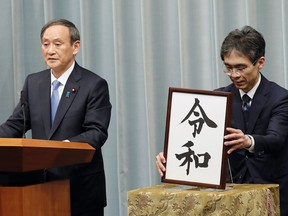Japan's Chief Cabinet Secretary Yoshihide Suga, left, speaks after he unveils the name of new era "Reiwa" at the prime minister's office in Tokyo, Monday, April 1, 2019. Japan says next emperor Naruhito's era name is Reiwa, effective May 1 when he takes the throne from his father.