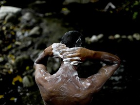 Angel Sanchez bathes in one of the streams that comes down from El Avila National Park, during interruptions in running water in Caracas, Venezuela, Wednesday, April 3, 2019. The park's invasion by desperate Caracas residents alarms environmentalists who fear it will leave irreversible damage.