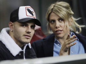 FILE - In this Thursday, Feb. 21, 2019, Inter Milan's Mauro Icardi is flanked by his wife Wanda Nara as they sit in the stands during the Europa League, round of 32, second leg soccer match between Inter Milan and SK Rapid Vienna, at the San Siro stadium in Milan, Italy. Mauro Icardi has been left off Inter Milan's squad for Sunday's match against Lazio following a six-week exile from the club. Icardi resumed training with Inter over the international break, having seemingly cleared up his differences with the club after being stripped of the captaincy amid protracted contract negotiations. So it was a surprise when Inter coach Luciano Spalletti announced Saturday that he now sees Icardi "like a new player as he was out for so long. I still hold that he can't be ready yet to help his teammates so he won't be in the squad tomorrow."