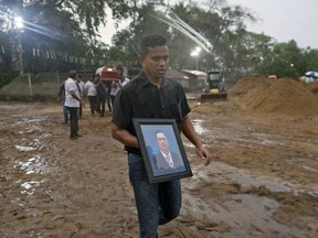 A relative carries a portrait of Calistas Fernando ahead his coffin for burial during the funerals of three people of the same family, all died at Easter Sunday bomb blast at St. Sebastian Church in Negombo, Sri Lanka, Monday, April 22, 2019. Easter Sunday bombings of churches, luxury hotels and other sites was Sri Lanka's deadliest violence since a devastating civil war in the South Asian island nation ended a decade ago.