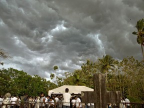 Dark clouds accumulate as people gather to bury three members of the same family, all died at Easter Sunday bomb blast at St. Sebastian Church in Negombo, Sri Lanka, Monday, April 22, 2019. Easter Sunday bombings of churches, luxury hotels and other sites was Sri Lanka's deadliest violence since a devastating civil war in the South Asian island nation ended a decade ago.