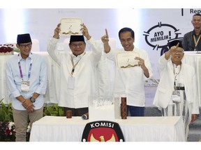 FILE - In this Sept. 21, 2018, file photo, Indonesian presidential candidates Prabowo Subianto, second from left, and his running mate Sandiaga Uno, left, Joko Widodo, second from right, and his running mate Ma'ruf Amin, show the ballot numbers that will represent them in the upcoming presidential election, during a draw at the General Election Commission office in Jakarta, Indonesia. Indonesia's presidential election Wednesday, April 17, 2019 is a re-run of the 2014 contest when Widodo, a furniture business owner who became Jakarta governor, vied with the former special forces general to lead the world's third-largest democracy and most populous Muslim-majority nation.