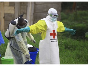 FILE - In this Sunday, Sept 9, 2018 file photo, a health worker sprays disinfectant on his colleague after working at an Ebola treatment center in Beni, eastern Congo.  Top Red Cross official Emanuele Capobianco said Friday April 12, 2019, that he's "more concerned than I have ever been" about the possible regional spread of the Ebola virus in Congo after a recent spike in cases.