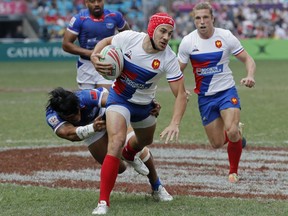 France's Gabin Villiere, center, is tackled by Samoa's Tofatu Solia during the semifinal match at the Hong Kong Sevens rugby tournament in Hong Kong, Sunday, April 7, 2019.