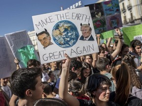 FILE - In this March 15, 2019 file photo, a student holds a sign showing images of U.S. President Donald Trump, right, and Brazil's President Jair Bolsonaro during a protest against what the students believe are their governments' failure to take tough action against global warming, in Madrid, Spain. As a congressman and candidate, Bolsonaro often questioned the reality of climate change and cast environmental groups as foreign-influenced meddlers restraining Brazil's economic growth by holding back mining and agriculture, stances that resemble those of Trump, who before taking office described the U.S. Environmental Protection Agency as a "disgrace" that largely should be dismantled.