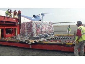In this image taken from video provided by the International Red Cross, airport employees unload the first shipment of humanitarian aid from the International Federation of Red Cross and Red Crescent Societies at the Simon Bolivar International Airport in Maiquetia, Venezuela, Tuesday, April 16, 2019. The Red Cross announced in late March that it had obtained permission from officials to begin delivering assistance to the crisis-stricken country. (International Committee of the Red Cross via AP)