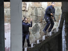 FILE - In this Jan. 2, 2019 file photo, Mexican police climb up a set of stairs of a dilapidated building during a shootout with a group of armed criminals in Acapulco, Mexico. Officials say homicides in Mexico rose by 9.7% in the first quarter of 2019 compared to the same period of 2018. President Andres Manuel Lopez Obrador said Monday, April 22, 2019, that he wants to reduce violence through social programs and a new militarized police force known as the National Guard.