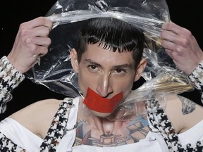 In this April 24, 2019 photo, a model tears a plastic bag from his head, as he wears a creation from the João Pimenta collection during Sao Paulo Fashion Week in Sao Paulo, Brazil.