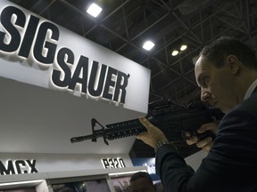 A man tries a Sig Sauer rifle, displayed at the LAAD Defense and Security International Exhibition in Rio de Janeiro, Brazil, Tuesday, April 2, 2019.
