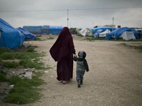 In this March 27, 2019, photo, Samira from Belgium walks with her son at Camp Roj in north Syria. She traveled to Syria, where Islamic State militants brought suitors for marriage. Samira chose a French citizen, Karam El-Harchaoui. Her husband now imprisoned for IS ties, she is trying to get home to Belgium. "What we saw with Daesh was a lesson to us and allowed us to gain perspective on the extremists. All we want is to reintegrate in our society," she said, using an Arabic acronym for IS.