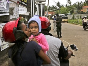 A Sri Lankan Christian mother kisses her daughter as they stop their two wheeler to have a look at the St. Sebastian's Church from outside where a suicide bomber blew himself up on Easter Sunday, in Negombo, north of Colombo, Sri Lanka, Sunday, April 28, 2019. Sri Lanka's Catholics celebrated Sunday Mass in their homes by a televised broadcast as churches across the island nation shut over fears of militant attacks, a week after the Islamic State-claimed Easter suicide bombings killed over 250 people.