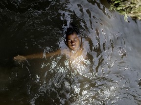 A children bathes in a brook in Caracas, Venezuela, Tuesday, April 2, 2019. Since a massive power failure struck on March 7, the nation has experienced near-daily blackouts and a breakdown in critical services such as running water and public transportation.