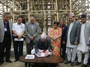 Nepal Prime Minister Khadga Prasad Oli writes his remarks in front of the Kasthamandap temple which collapsed in the 2015 earthquake, during a function to mark the anniversary of the quake in Kathmandu, Nepal, Thursday, April 25, 2019. The violence of the 7.8-magnitude earthquake killed nearly 9,000 people and left countless towns and villages across central Nepal in shambles.