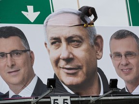 A man works on a Likud party election campaign billboard depicting Israeli Prime Minister Benjamin Netanyahu, center, and his party candidates, in Petah Tikva, Israel, Monday, April 1, 2019.