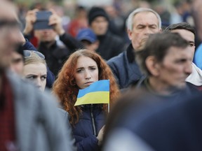 A woman holds an Ukrainian flag as protesters gather to march to the Olympic stadium ahead of debates between two candidates in the weekend presidential run-off in Kiev, Ukraine, Friday, April 19, 2019. Friday is the last official day of election canvassing in Ukraine as all presidential candidates and their campaigns will be barred from campaigning on Saturday, the day before the vote.