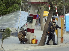 An Afghan Security personnel, left, aims his weapon outside the Telecommunication Ministry during a gunfight with insurgents in Kabul, Afghanistan, Saturday, April 20, 2019. A suicide blast rocked Afghanistan's capital Saturday during a gun battle with security forces, officials said, killing several people a day after hopes for all-encompassing peace talks collapsed.