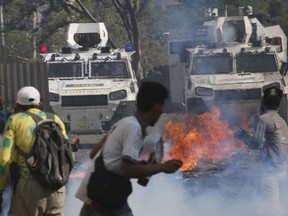 Opponents to Venezuela's President Nicolas Maduro face off with Bolivarian National Guards in armored vehicles who are loyal to the president, during an attempted military uprising in Caracas, Venezuela, Tuesday, April 30, 2019. Opposition leader Juan Guaido took to the streets with a small contingent of heavily armed troops in a call for the military to rise up and oust Maduro.
