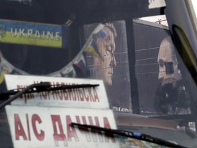 A bus drives past a billboard depicting Ukraine's President Petro Poroshenko and Russian President Vladimir Putin looking at each other in Kiev, Ukraine, Wednesday, April 17, 2019. The second round of presidential vote in Ukraine will take place on April 21.