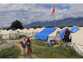 In this Monday, April 1, 2019, photo, Indonesian women chat among tents at a temporary shelter for those affected by the Sept. 28, 2018, earthquake and liquefaction in Palu, Central Sulawesi, Indonesia. Six months after the city was ripped apart by an earthquake, tsunami and liquifying soil that sucked neighborhoods into the earth, thousands of people are living in sweltering tent cities and almost a third of temporary housing is unoccupied after aid groups and authorities failed to connect it to water or electricity.