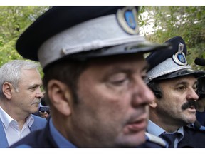 Liviu Dragnea, the leader of Romania's ruling Social Democratic party, left, leaves escorted by police officers after a court hearing in Bucharest, Romania, Monday, April 15, 2019. The High Court for Cassation and Justice has postponed a verdict in the trial of the country's most powerful politician accused of intervening from 2006-2012 to keep two women on the payroll of a family welfare agency, even though they were working for his party instead.
