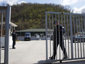 Kosovo police officer secures the area of a detention center where authorities brought back from Syria 110 Kosovar citizens, mostly women and children in the village of Vranidol on Sunday, April 20, 2019.  Four suspected fighters have been arrested, but other returnees will be cared for, before being sent to homes over the coming days according to Justice Minister Abelard Tahiri.