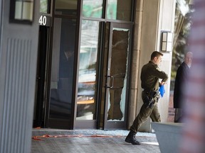 Investigators walk past the shattered glass from the front entrance to the Sheraton in Laval Sunday morning. On Saturday night, May 4, Mafia-linked Salvatore Scoppa, was shot there and pronounced dead at the hospital.