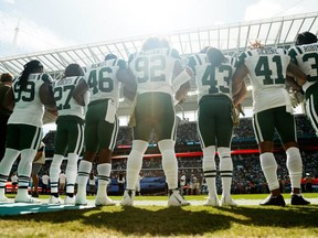 New York Jets players link arms during the national anthem prior to their game against the Miami Dolphins at Hard Rock Stadium on November 4, 2018 in Miami, Florida.