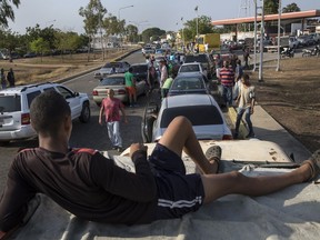 People line the street with their vehicles as they wait to fill up with gas at a fuel station, top right, in Cabimas, Venezuela, Wednesday, May 15, 2019. U.S. sanctions on oil-rich Venezuela appear to be taking hold, resulting in mile-long lines for fuel in the South American nation's second-largest city, Maracaibo.