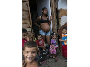Families gather outside their homes in the "Aguerridos Liberator" shanty town in Caracas, Venezuela, Thursday, May 9, 2019. In the fourth month of their standoff, Venezuela's President Nicolas Maduro and opposition leader Juan Guaidó are unable to deliver a knock-out blow as Venezuela spirals deeper into neglect, isolation and desperation.