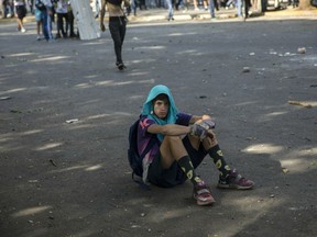 An anti-government protester rests during clashes with National Guard forces near La Carlota airbase in Caracas, Venezuela, Wednesday, May 1, 2019. Opposition leader Juan Guaido called for Venezuelans to fill streets around the country Wednesday to demand President Nicolas Maduro's ouster. Maduro is also calling for his supporters to rally.