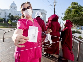 Laura Stiller hands out coat hangers as she talks about illegal abortions during a rally against HB314, the near-total ban on abortion bill, outside of the Alabama State House in Montgomery, Ala., on Tuesday, May 14, 2019.