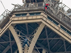 TOPSHOT - A man climbs to the top of the Eiffel Tower, in Paris, without any protection as a firefighter  looks down at him from the top, on May 20, 2019.