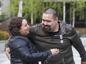 In this Saturday, May 18, 2019, photo, Nome Magistrate Judge Pamela Smith gets a hug from her friend, George "Radar" Lambert after Lambert was given a Silver Lifesaving Medal at the Atwood Building courtyard in Anchorage, Alaska. Lambert was awarded the medal by the U.S. Coast Guard for saving Smith from drowning in Kotzebue in 1998, when he was 10 and she was 12.