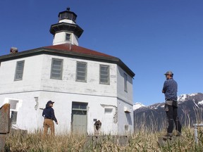 In this Monday, April 29, 2019 photo Eldred Rock Lighthouse Preservation Association Executive Director Sue York speaks to Marine Exchange of Alaska Field Operations Supervisor Nick Hatch at Eldred Rock Lighthouse. Cruise and ferry passengers, as well as locals passing through, can't help but look at the octagonal, white and red structure atop a craggy cliff in the middle of Lynn Canal. If they were able to stop and look closer at the 114-year-old lighthouse, they'd see the bright white paint is peeling and that's the least of the concerns, Eldred Rock Lighthouse Preservation Association board member Justin Fantasia said.