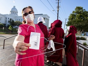 Laura Stiller hands out coat hangers as she talks about illegal abortions during a rally against a ban on nearly all abortions outside of the Alabama State House in Montgomery, Ala., on Tuesday, May 14, 2019. The legislation would make performing an abortion a felony at any stage of pregnancy with almost no exceptions.