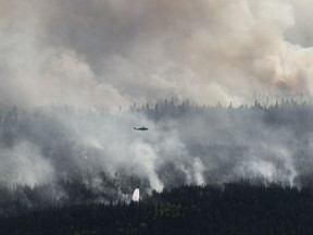 A helicopter drops a bucket of water on the Chuckegg Creek wildfire west of High Level, Alta., in a Saturday, May 25, 2019, handout photo.